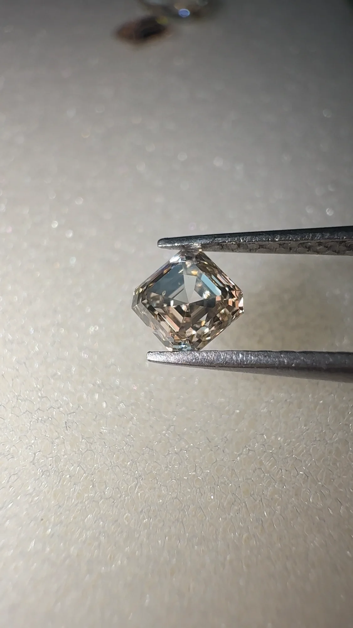 A second champagne asscher cut diamond in tweezers