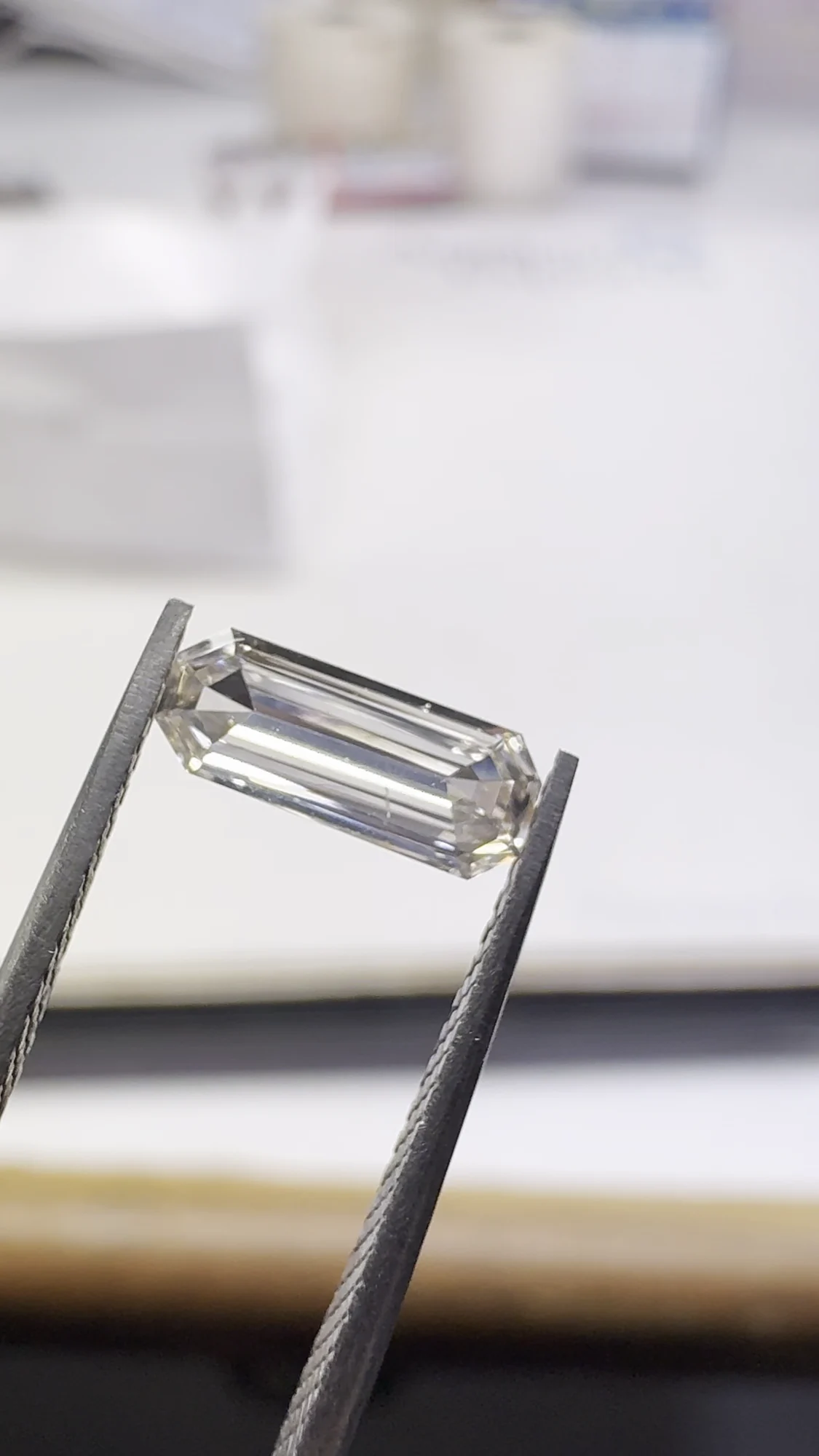 Elongated emerald cut diamond in tweezers