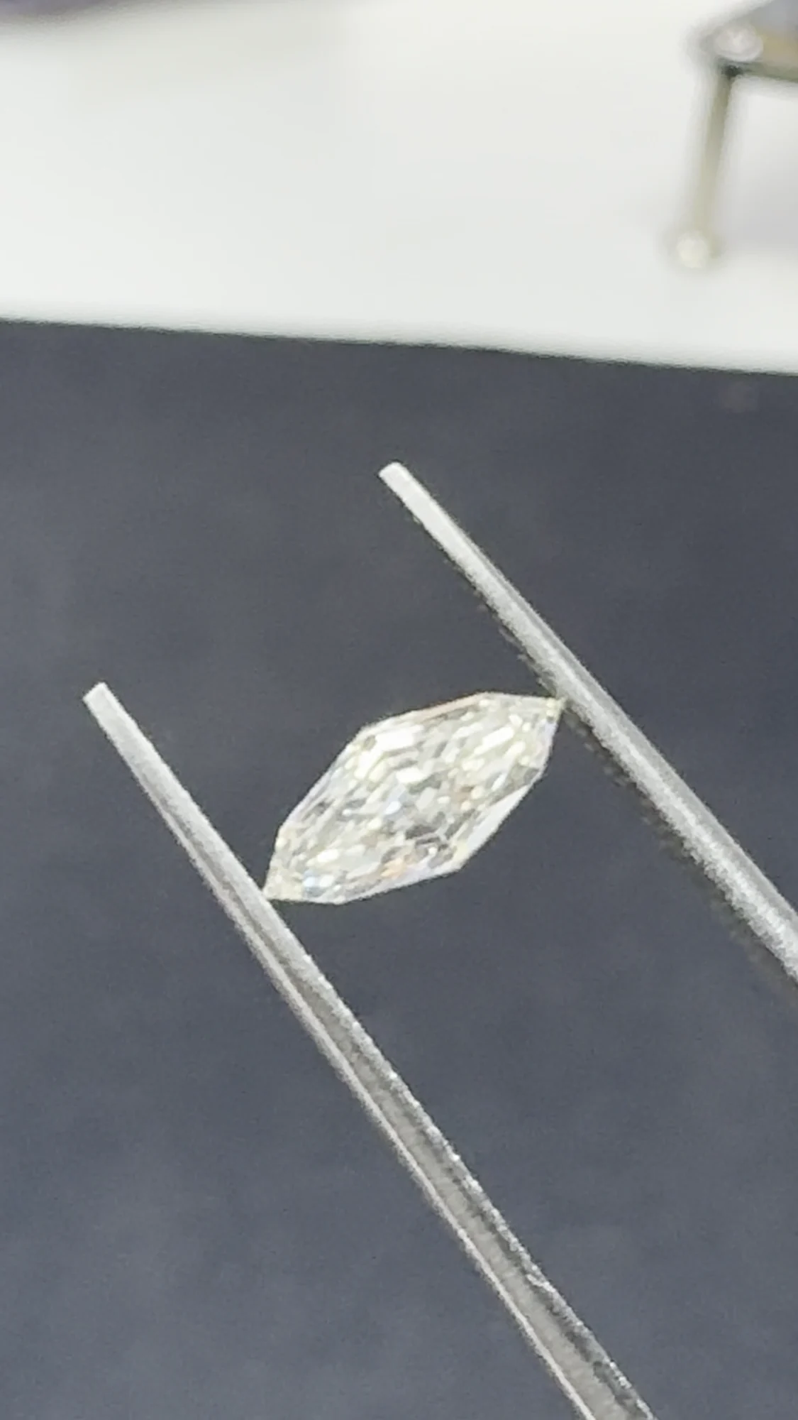 White step-cut marquise diamond in tweezers