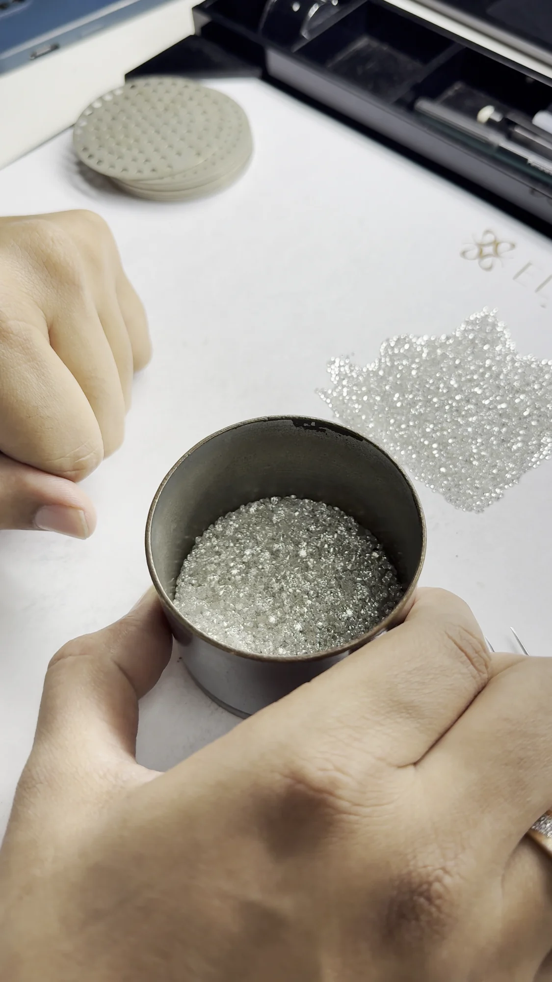 Polished melee diamonds in a sieve can on the sorting desk