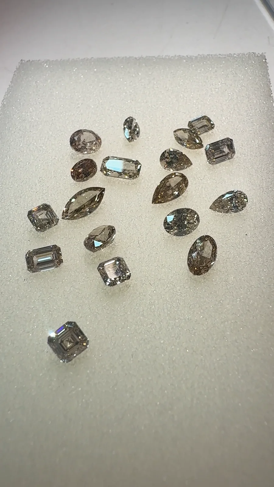 Fancy colour diamonds in several shapes laid out on our desk